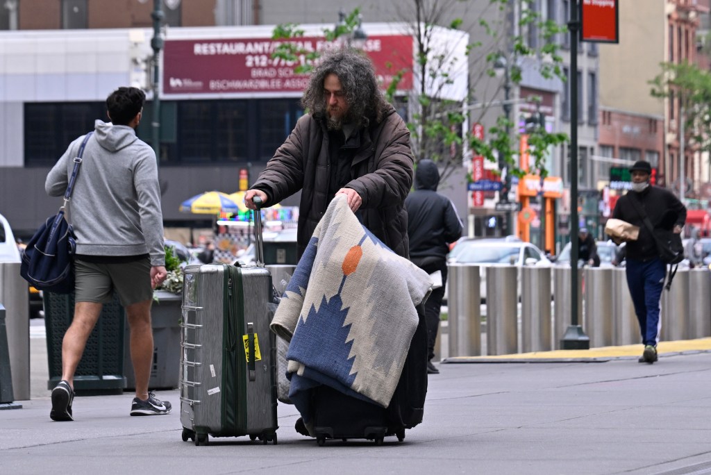 Homeless man pushes his belongings across from Penn Station.