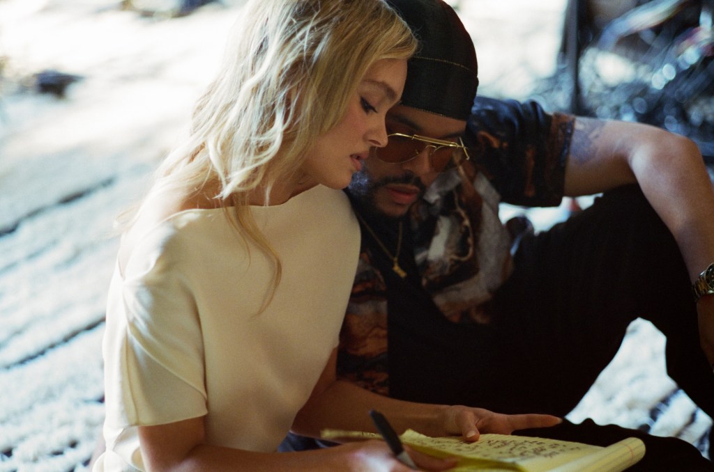 Lily Rose Depp and The Weeknd, aka Abel Tesfaye, in "The Idol" sit close together. 