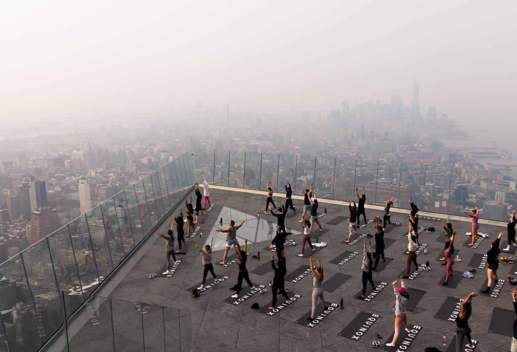 People brave the smoke while attending a morning yoga class on The Edge observation deck overlooking Manhattan.