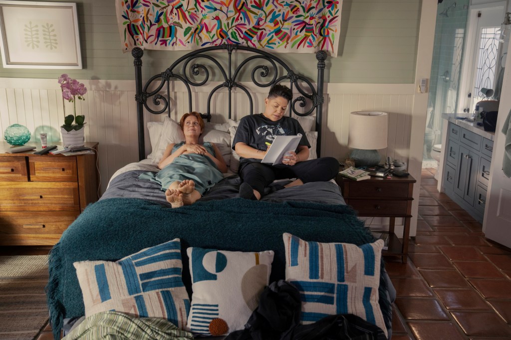 Miranda (Cynthia Nixon) with her lover, unpopular character Che Diaz (Sara Ramirez) in bed next to each other reading. 