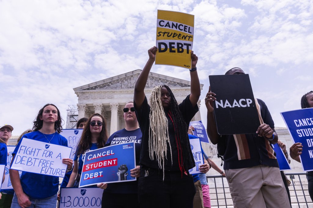 Protesters holding signs advocating for the cancellation of student debt stand in front of the United States Supreme Court