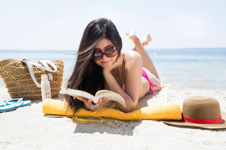 Young woman reading book on beach