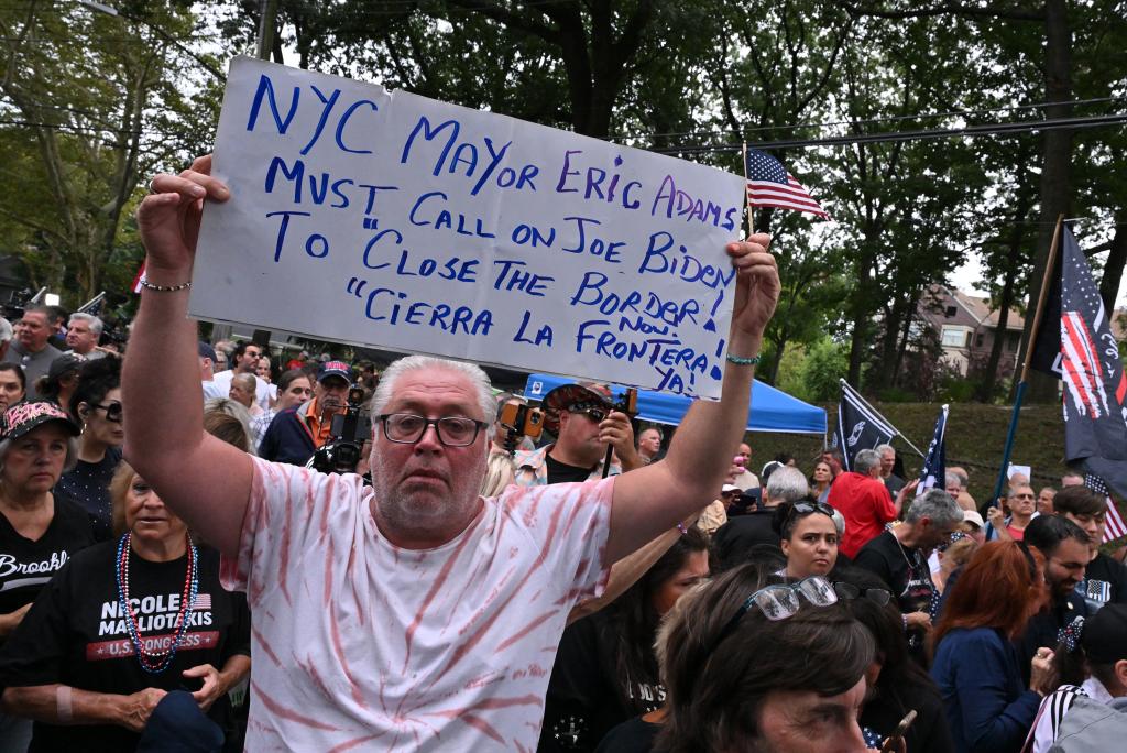 A protester's sign calls on the mayor to demand President Biden close the border.