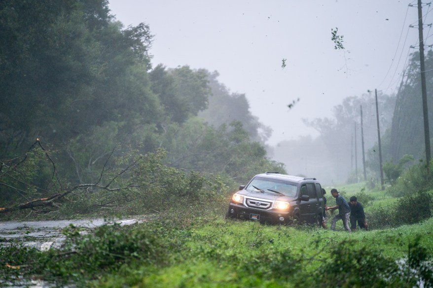 People working to free a car stuck on the shoulder of a road near Mayo, Florida.