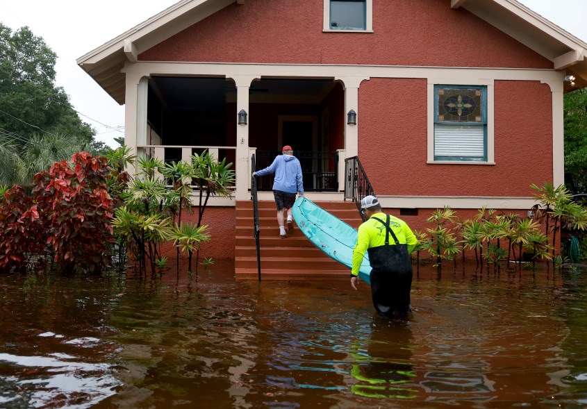 David Rudd helps Steve Odom carry a kayak onto his porch in Tarpon Springs.