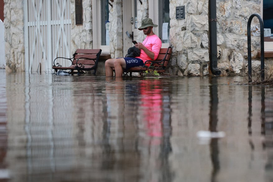 Florida resident Eliah Corcoran sits on a bench with flood waters up to his knees in the wake of Hurricane Idalia.