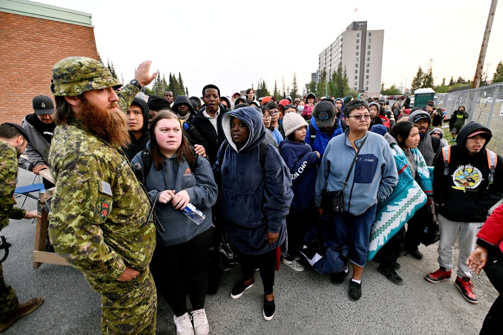 People line up outside of a local school to register to be evacuated, as wildfires threatened the Northwest Territories town of Yellowknife, Canada, on Aug. 17, 2023.