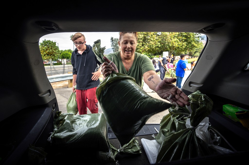 Rebecca Glaser and her son Jaden Fitzpatrick, 16, load sandbags into her SUV at Wildwood Park in San Bernardino, Ca., Saturday, Aug. 19.