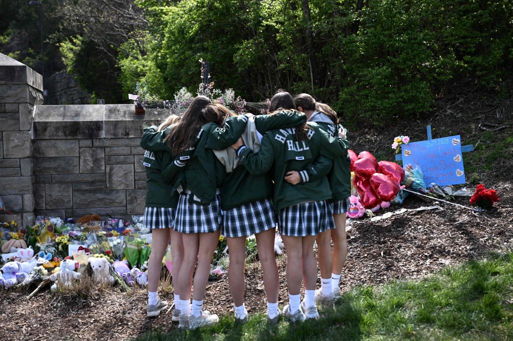 Girls embrace in front of a makeshift memorial for victims by the Covenant School building at the Covenant Presbyterian Church following a shooting, in Nashville, Tennessee, March 28, 2023. 