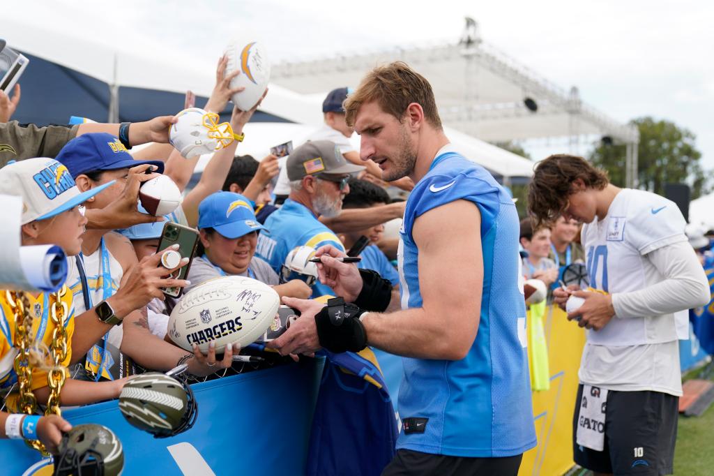 Los Angeles Chargers linebacker Joey Bosa (97) and quarterback Justin Herbert (10) sign autographs for fans.