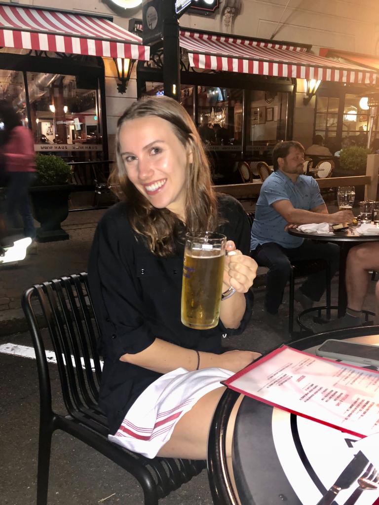 Grace Adams, 25, living on the Upper East Side, holding a beer mug at a restaurant in New York City. 