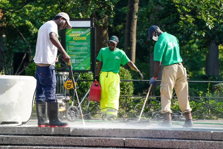 Workers this morning power wash paint off potted plants and sidewalk in Union Square Park