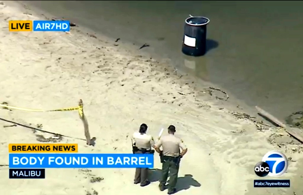 This image taken from video and provided by KABC-7 TV shows law enforcement officers stand by a barrel containing a man's body at Malibu Lagoon on July 31, 2023