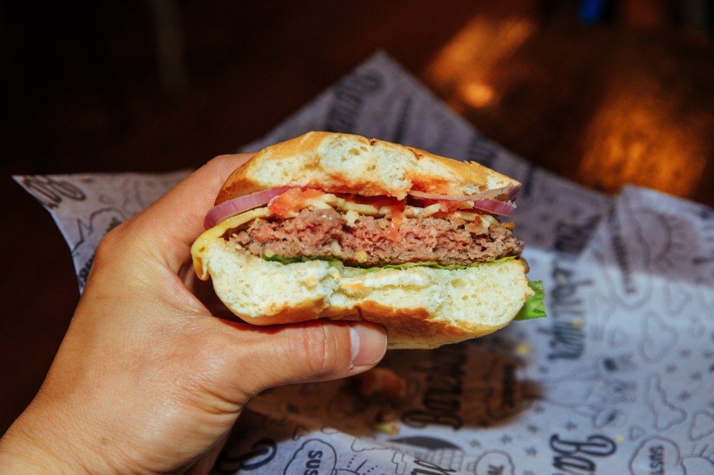 Hand holding a half eaten Impossible Burger. 