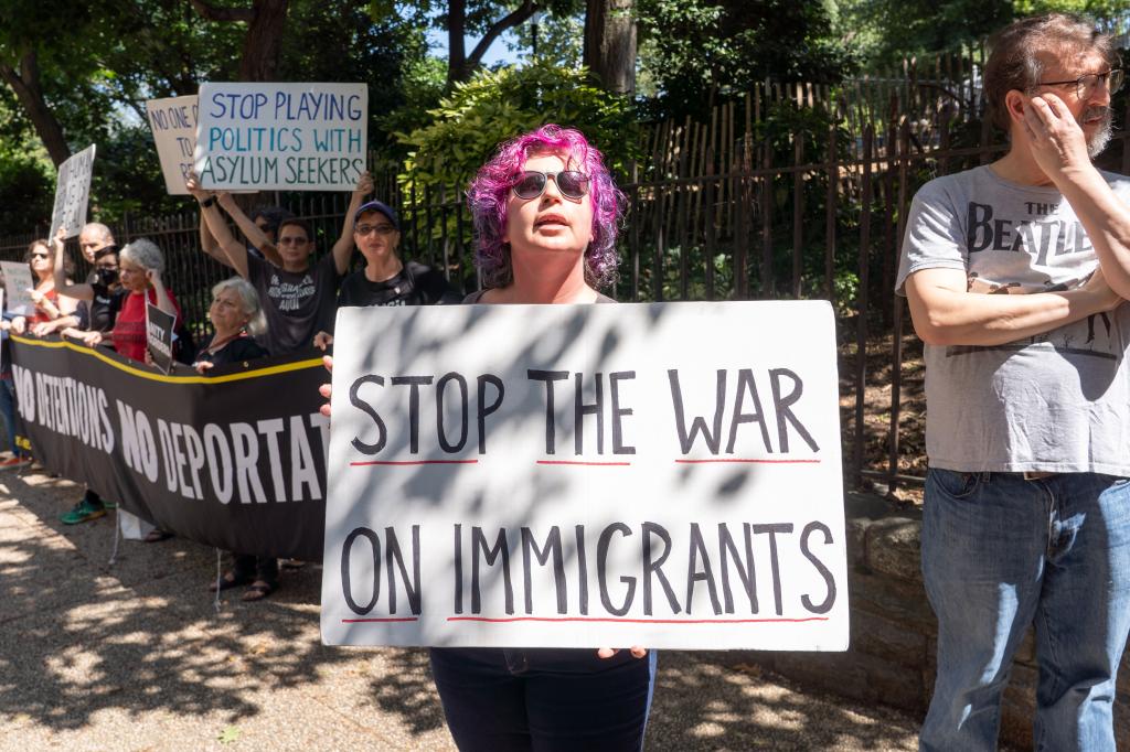 A counter-protestors holds a sign demanding that the other side "Stop the war on immigrants."