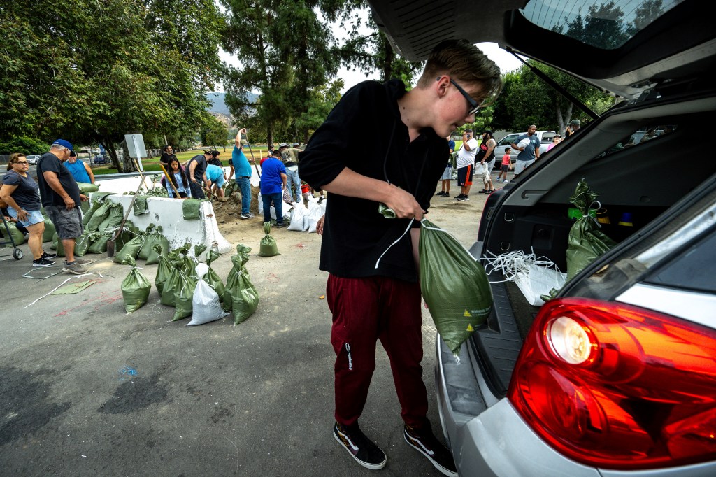 California resident pick up sandbags from a San Bernardino park as the state prepares for the storm that could bring “catastrophic and life-threatening” flooding to the region.