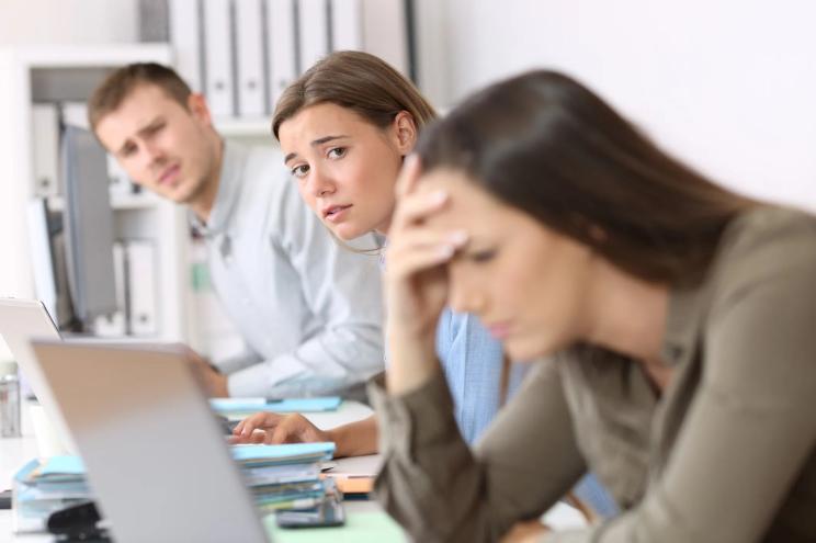 Sad workers looking at a frustrated colleague.