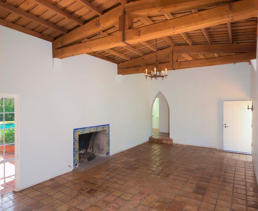 Original details include vaulted ceilings, exposed wood, the fireplace outline, and terra cotta floors.