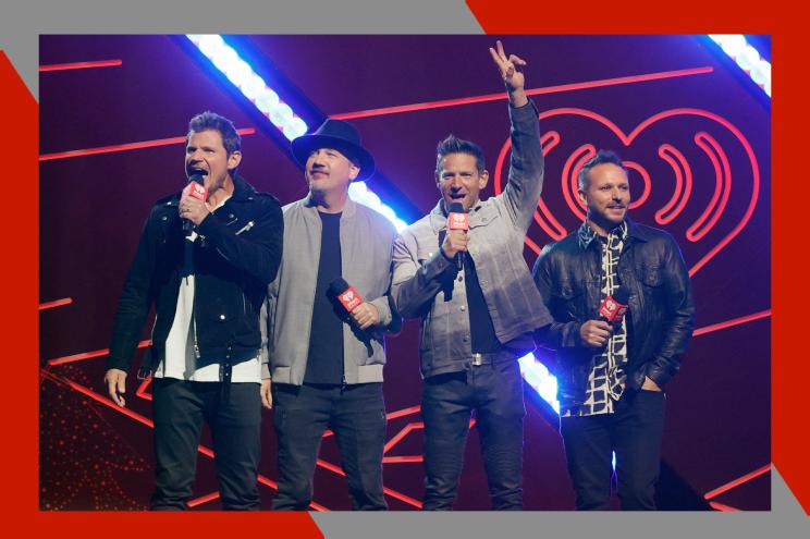 (L-R) Nick Lachey, Justin Jeffre, Jeff Timmons and Drew Lachey of 98 Degrees stand onstage together with microphones in hand.