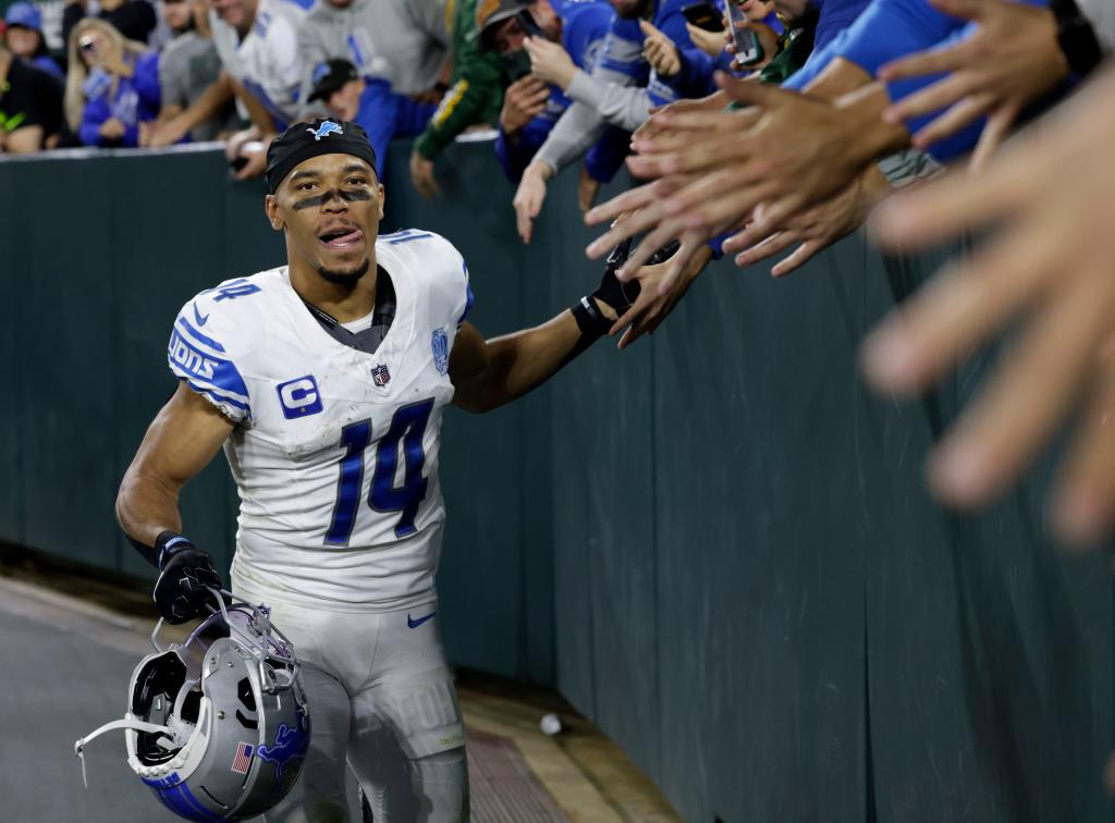 Amon-Ra St. Brown celebrates with fans after the Lions' win over the Packers at Lambeau Field.