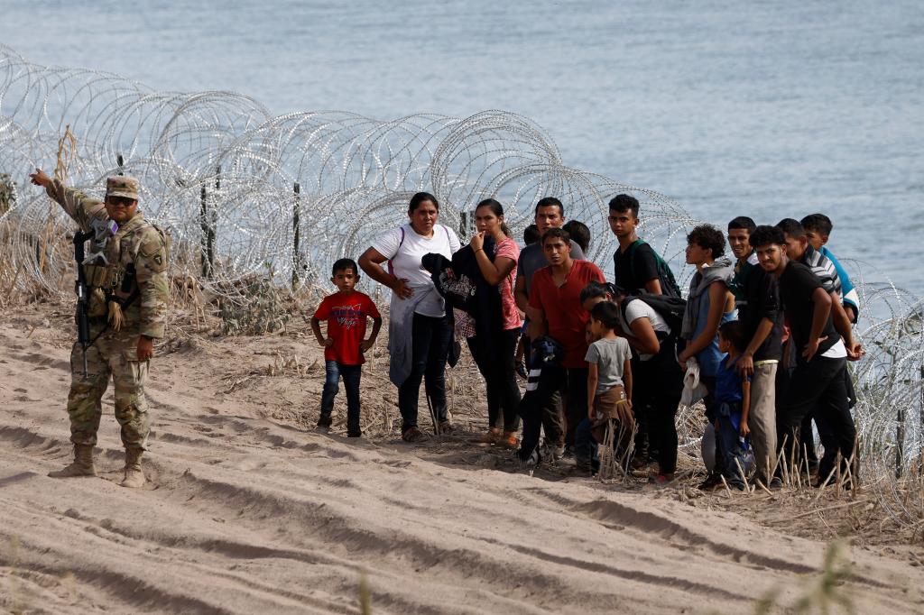 A Texas guardsmen holds a group of migrants after they crossed the Rio Grande into the United States from Mexico on July 31.