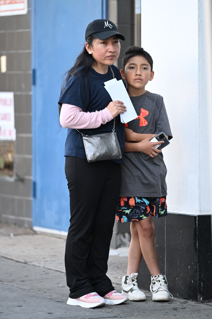 A mother and son wait with paperwork outside Jamaica school enrollment center.