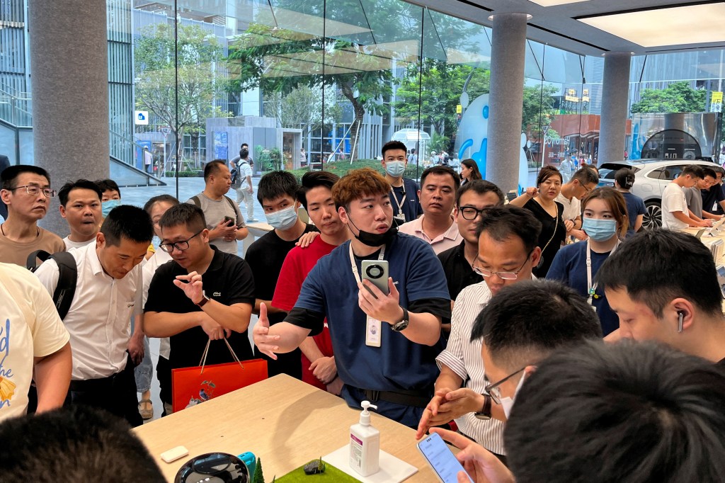 A staff member introduces the new Huawei Mate 60 smartphone to customers at the Huawei flagship store in Shenzhen, Guangdong province, China August 30, 2023. 