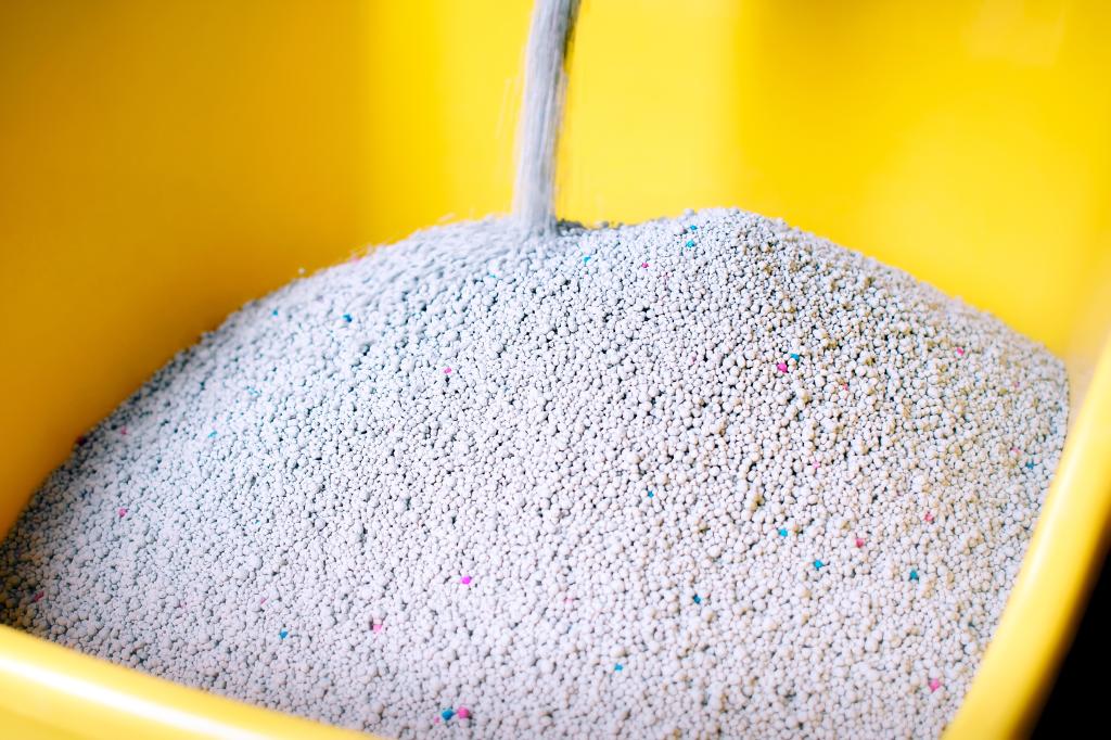 Photo of cat litter being poured into a yellow container.