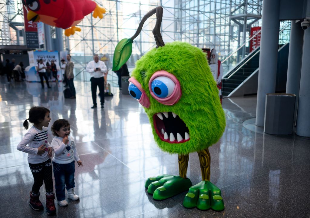 Two children interact with a giant doll at the 2019 Toy Fair.