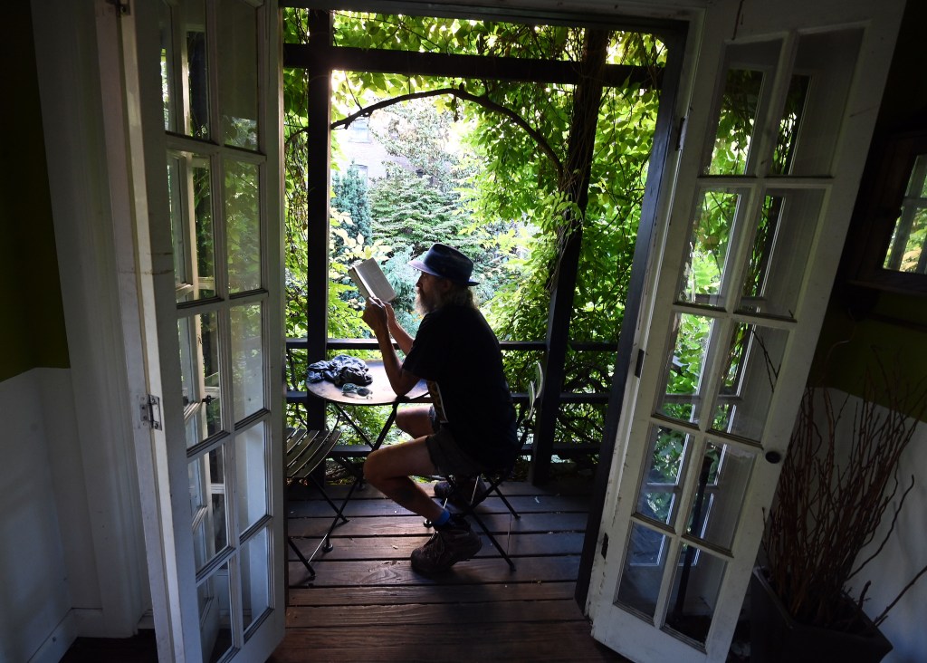 A local sits down at the table in the tree house reading a book. 