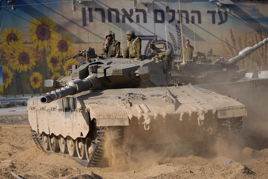 Israeli soldiers move a tank at a staging area near the border with Gaza Strip, in southern Israel on Sunday, Oct. 15, 2023. 