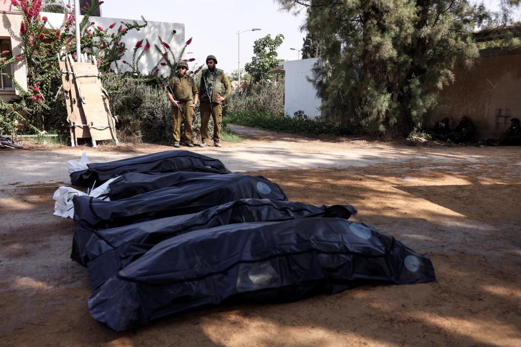 Israeli soldiers guard the bodies of Hamas victims