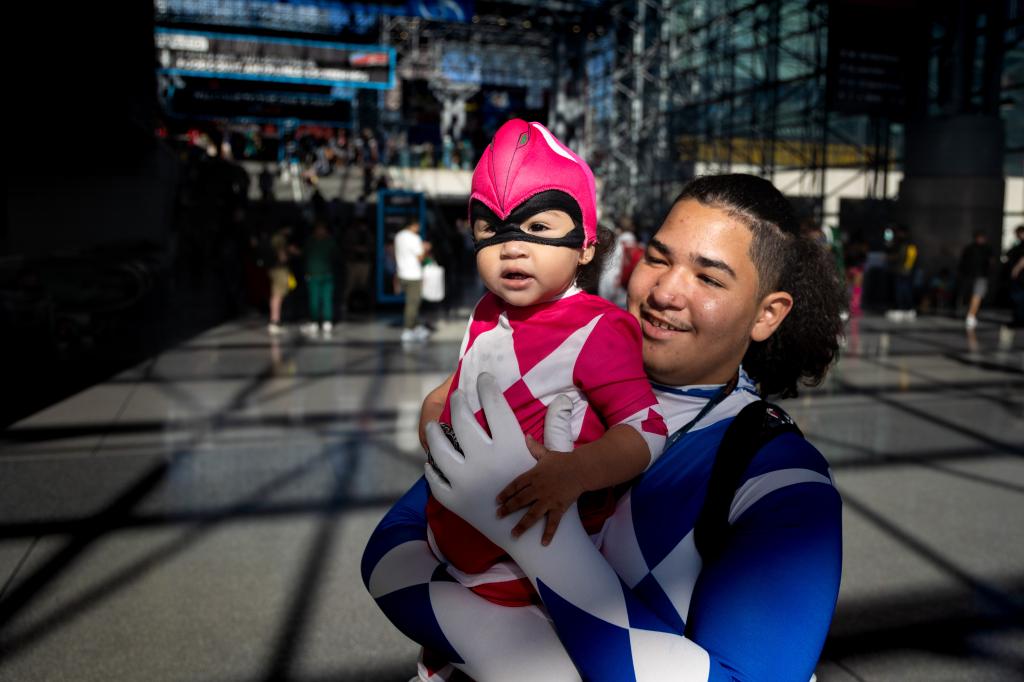 a one year old girl is held by her teenage brother while they both wear coordinated costumes