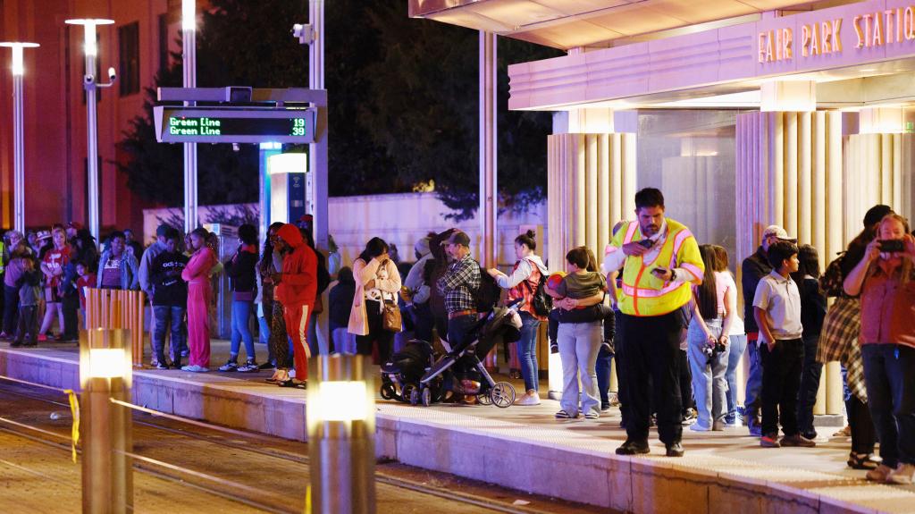 Festival goers wait for the DART Light Raill to arrive at the Fair Park Station following the shooting.