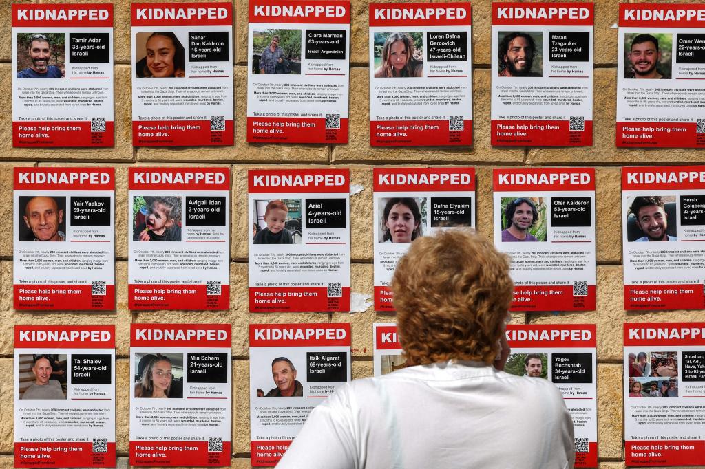 A woman in Tel Aviv looks at posters showing the pictures of Israeli hostages held by Palestinian militants.