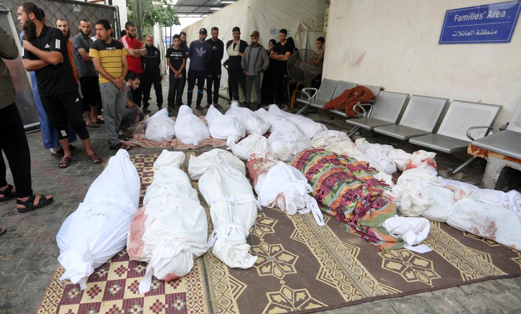 People standing near bodies of Palestinians killed by airstrikes in Rafah.