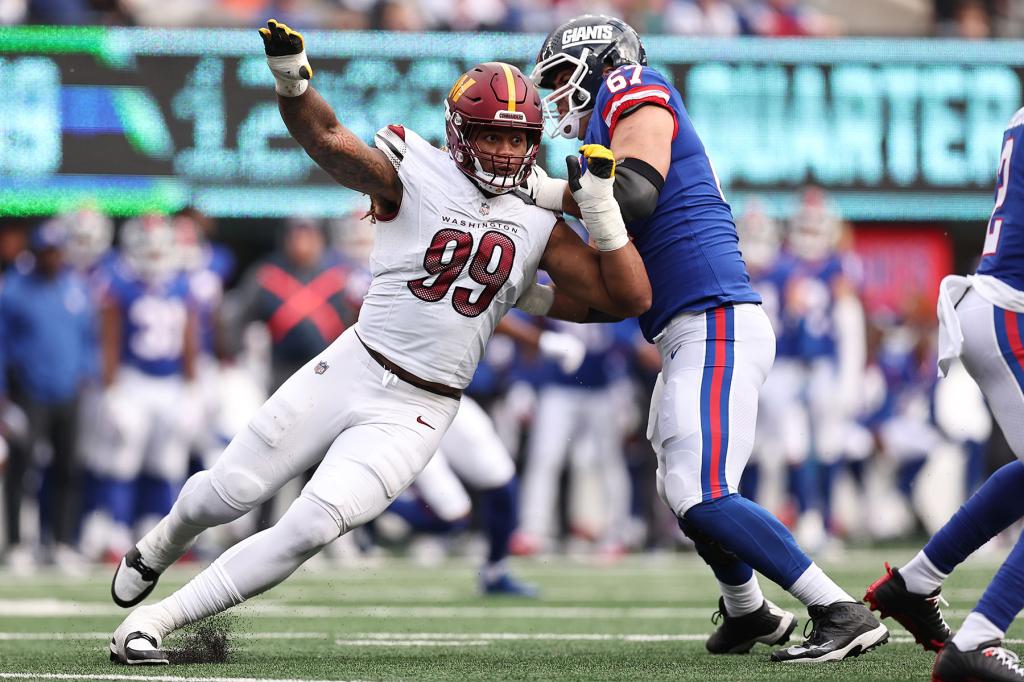 Wyatt Davis #67 of the New York Giants tackles Chase Young #99 of the Washington Commanders in the second half at MetLife Stadium on October 22, 2023 in East Rutherford, New Jersey. 