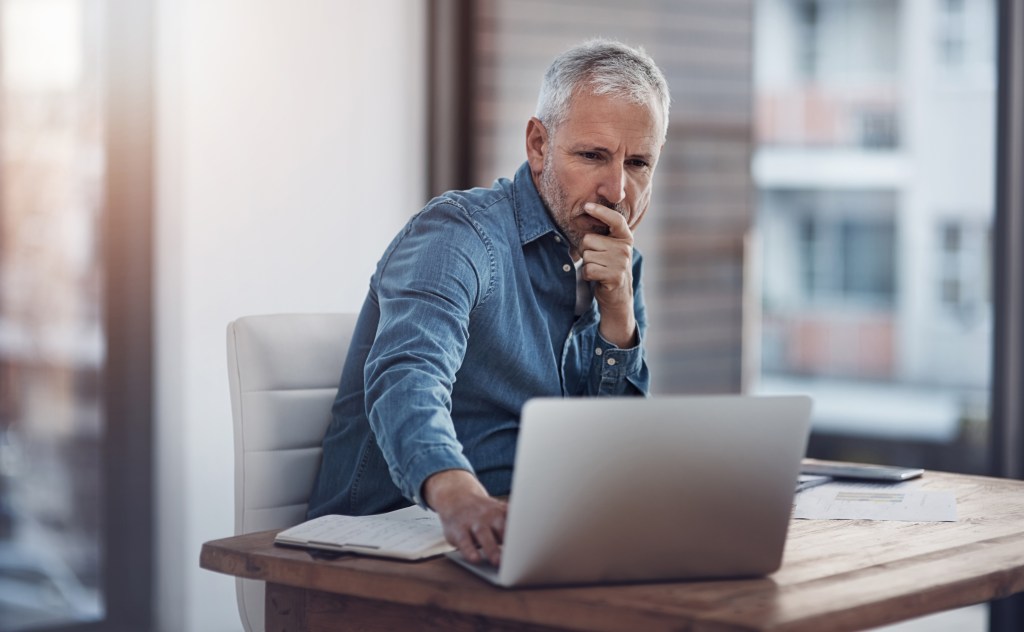 Cropped shot of a thoughtful mature businessman working on a laptop in an office