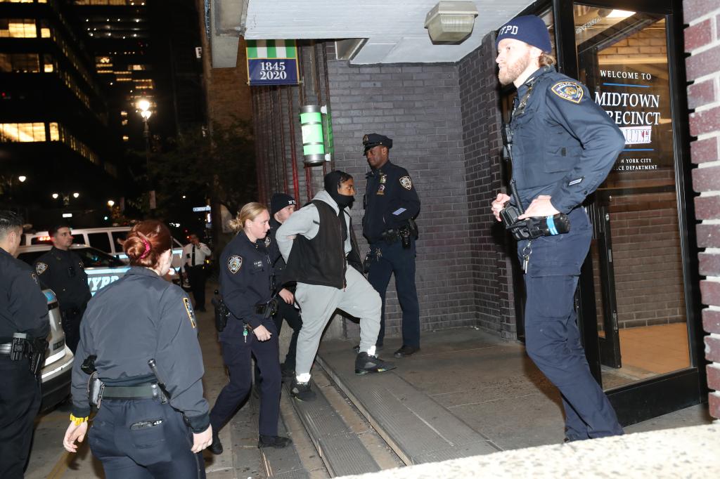 Another suspect in handcuffs is being led by police into the Midtown South Precinct on Oct. 31, 2023. 