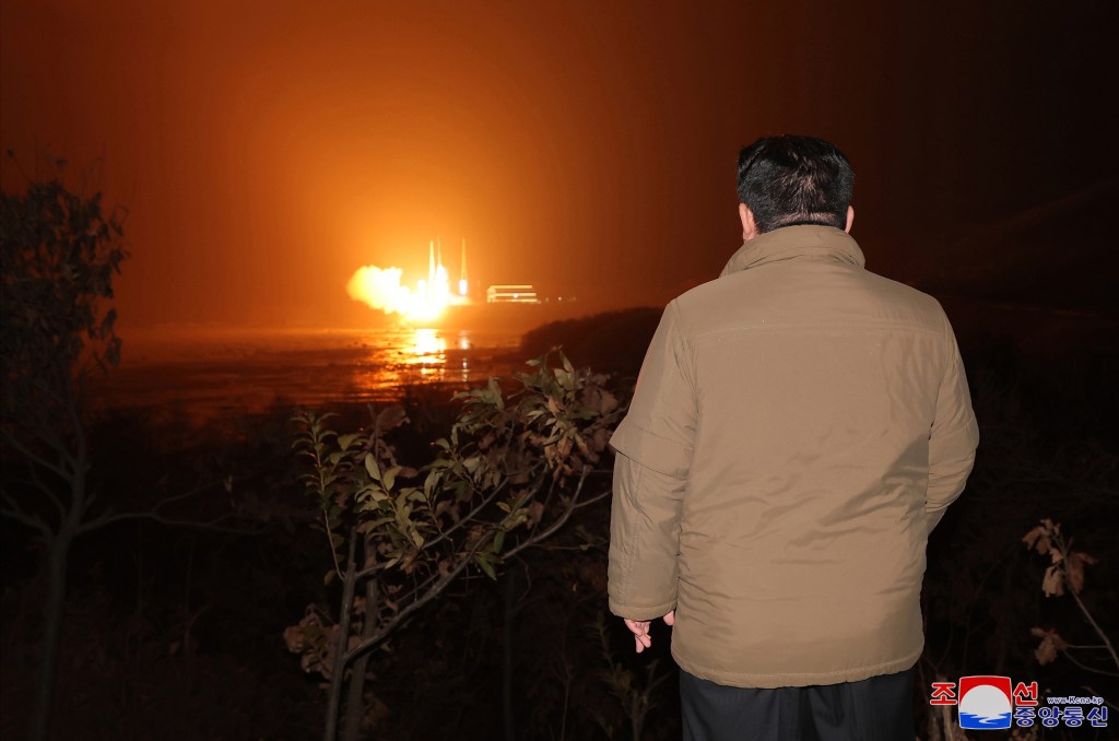 North Korean leader Kim Jong Un watches as the new-type carrier rocket "Chollima-1" carrying the spy satellite launches.