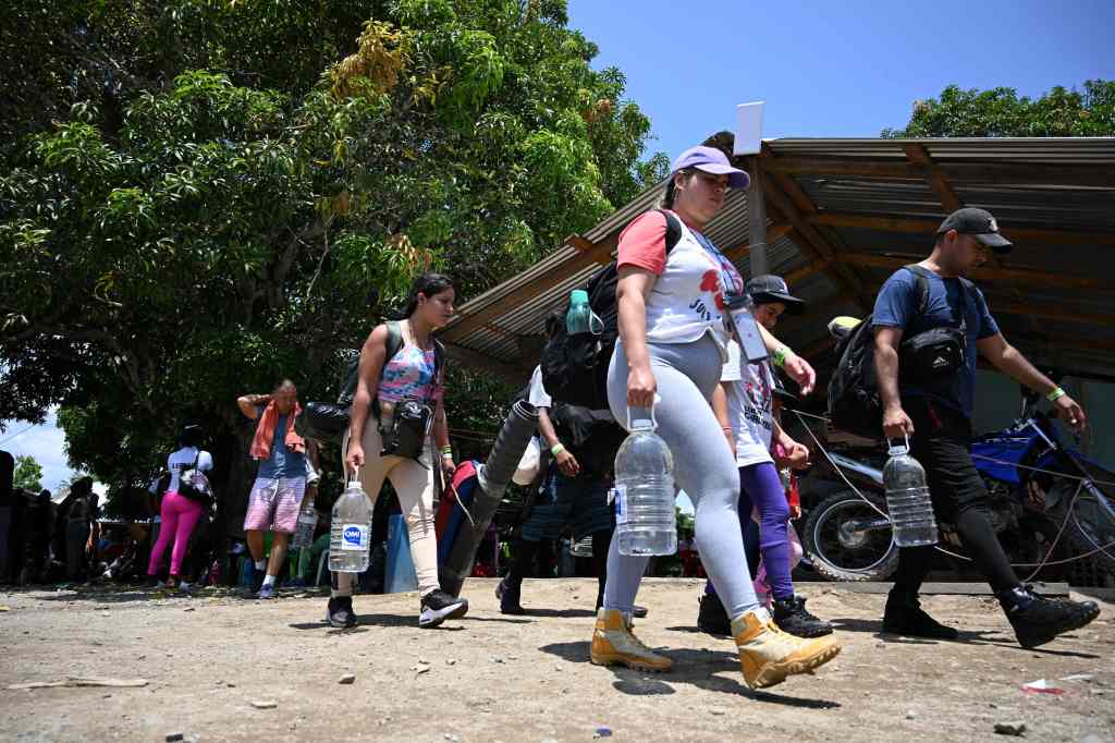 Migrants walking carrying water.