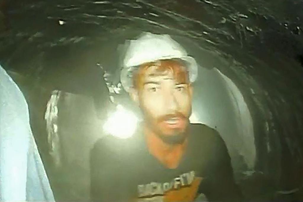 A blurry photo of a man wearing a hardhat inside a tunnel. He is one of the workers trapped inside the collapsed tunnel in India.