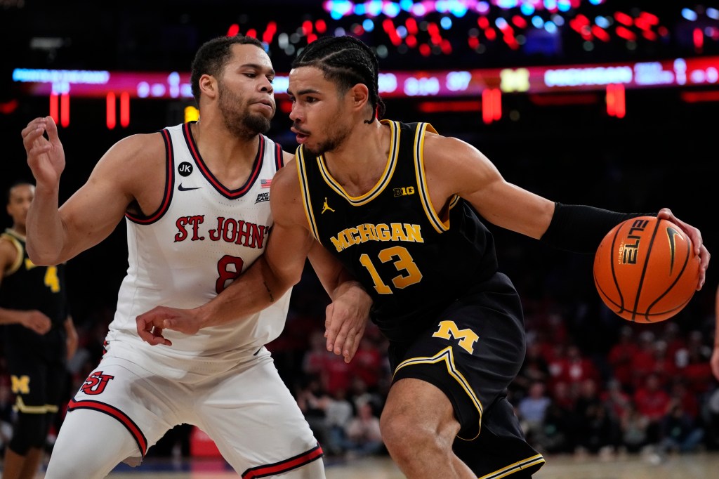 Michigan's Olivier Nkamhoua (13) drives past St. John's Chris Ledlum (8) during the first half of an NCAA college basketball game Monday, Nov. 13, 2023, in New York.