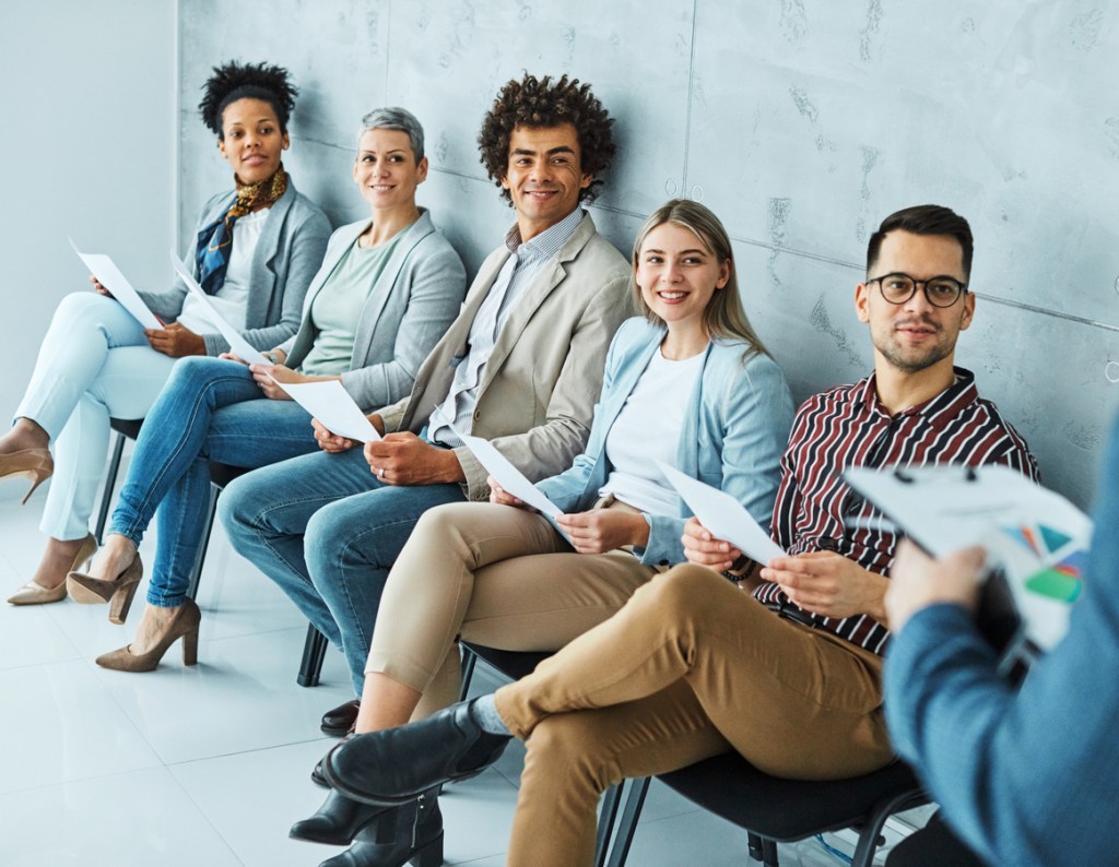 Group of young business people sitting in chairs and waiting for an interview.