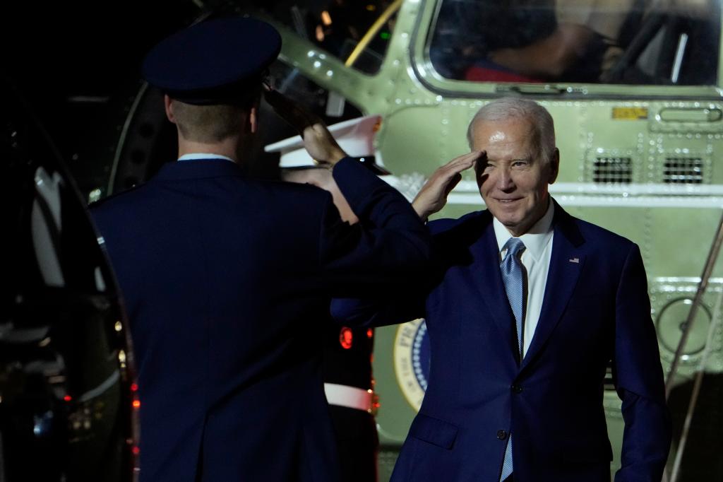 President Joe Biden salutes a Marine with his back to the camera. 