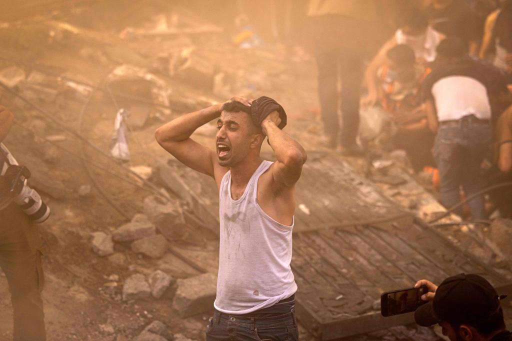 A Palestinian man reacts as others check the rubble of a building in Khan Yunis