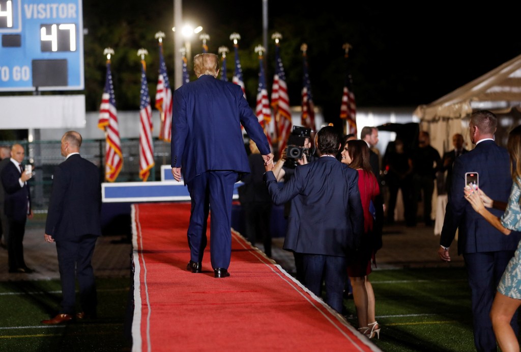 Donald Trump holds Donald Trump Jr.'s hands during a campaign rally at Ted Hendricks Stadium in Hialeah, Florida, U.S. November 8, 2023. 