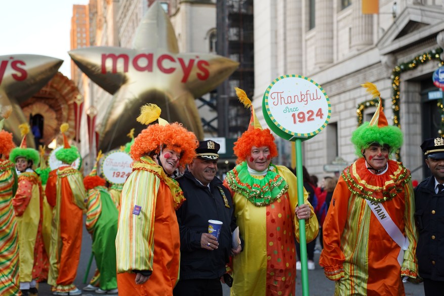 Macy's clown pose with an NYPD officer along the Macy's Thanksgiving Day Parade route.