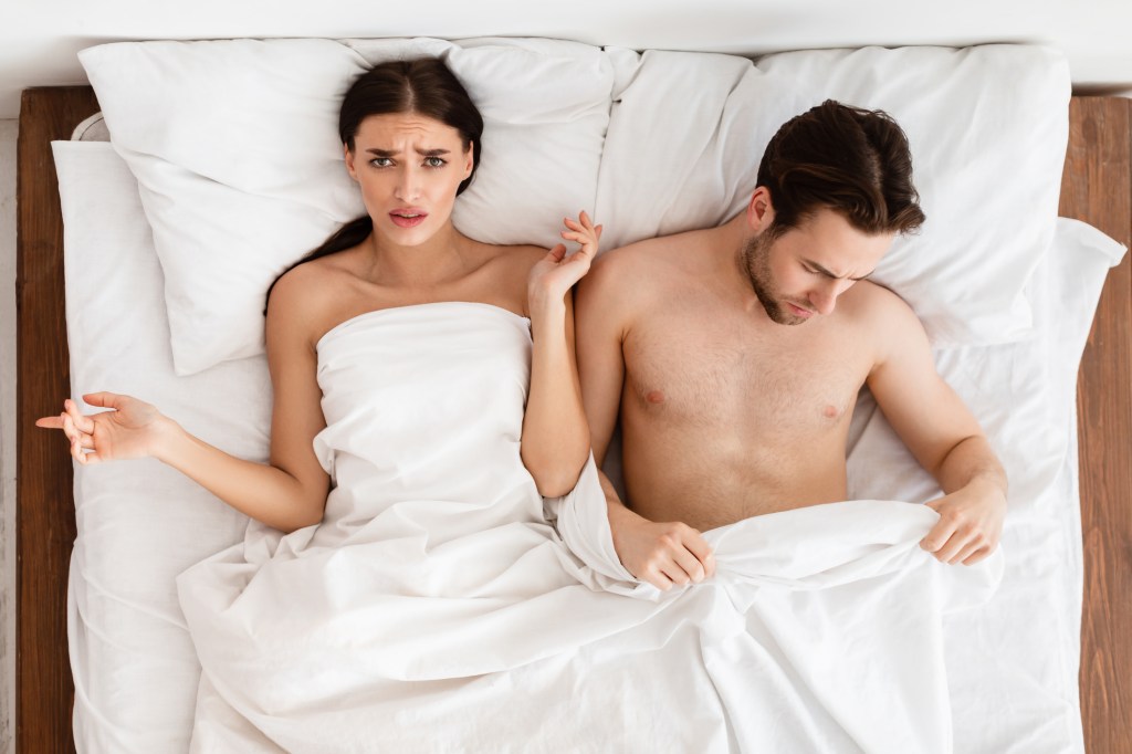 Displeased Girlfriend Lying Near Boyfriend With Erectile Dysfunction In Bed Indoor.