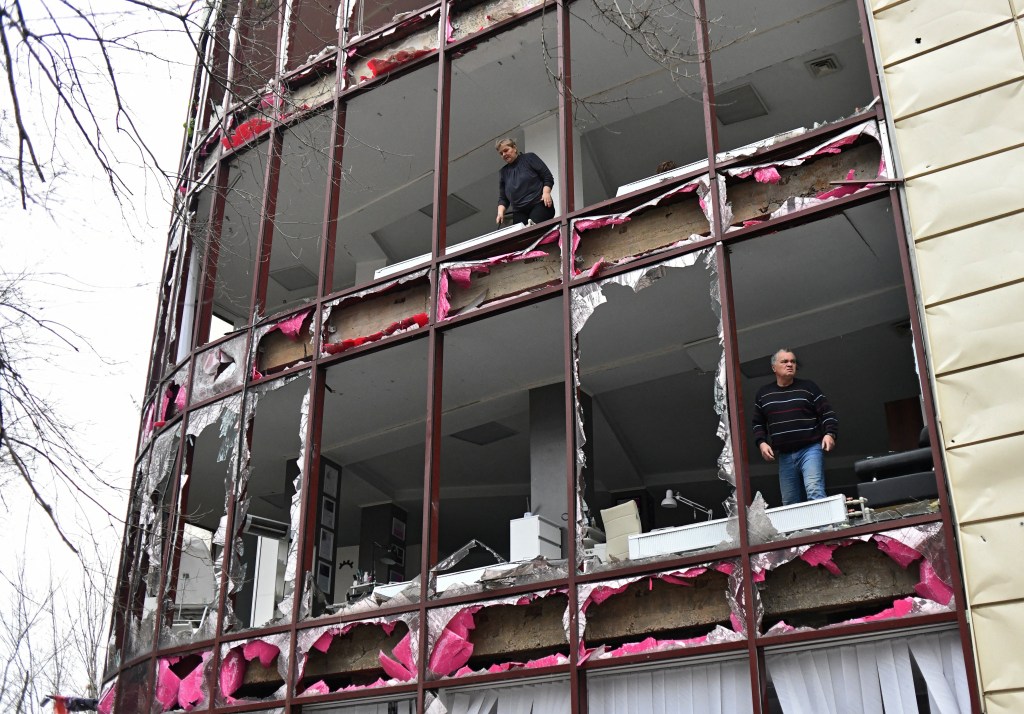 People remove debris inside a building housing a beauty salon, following recent shelling in the course of Russia-Ukraine conflict in Donetsk.